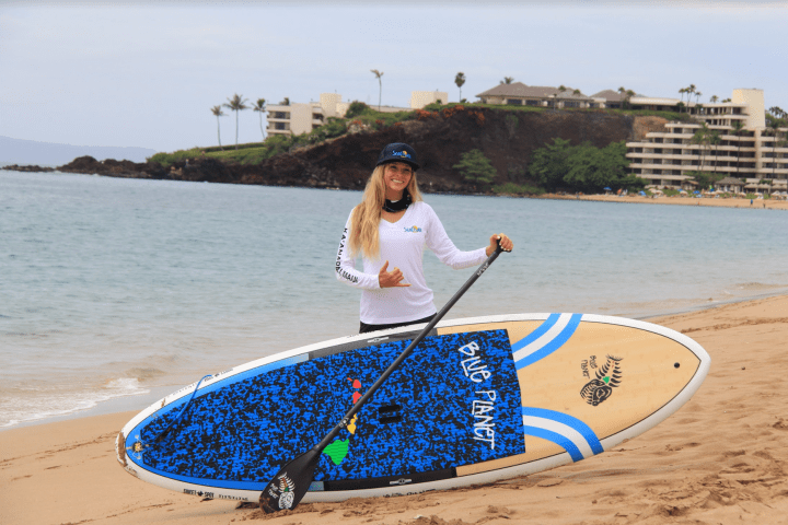 a person carrying a surf board on a body of water