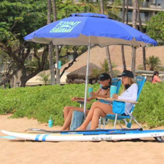 a group of people sitting at a table with a blue umbrella
