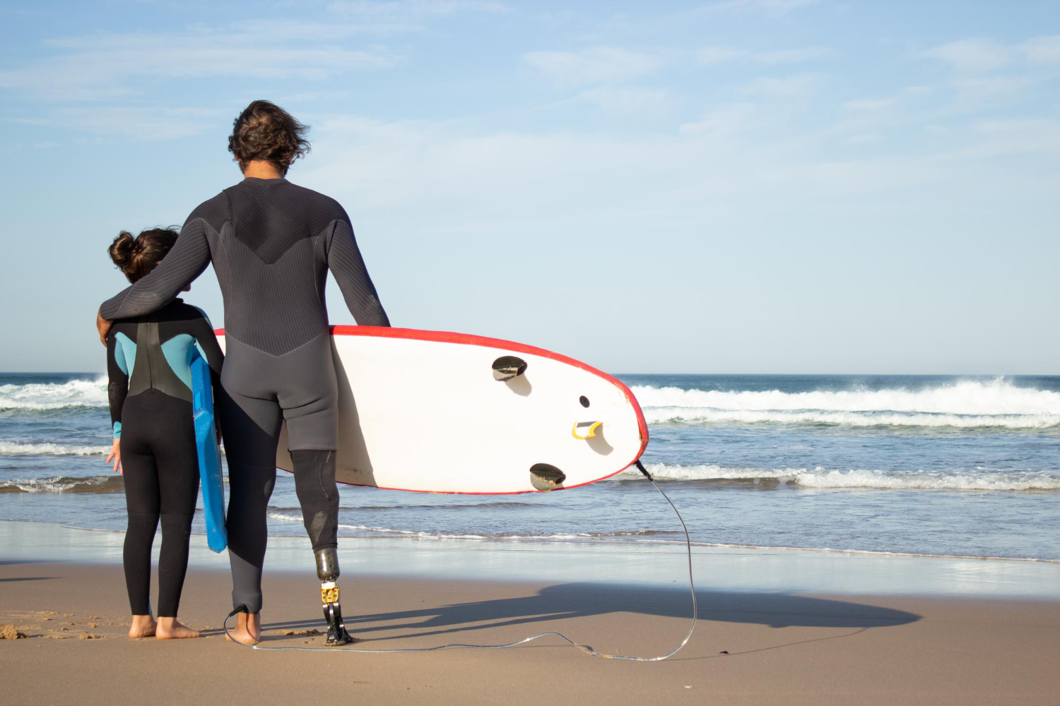 kids surf lessons in Maui a person standing on a beach holding a surf board