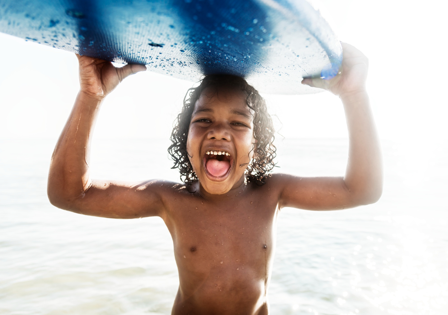 little-boy-carrying-surfboard a man holding a frisbee in a body of water